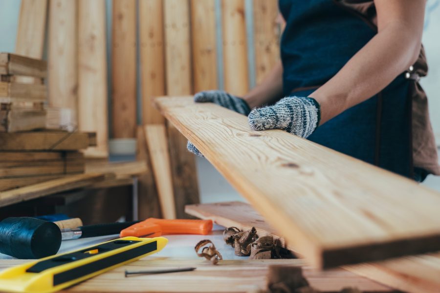 Carpenter working with equipment on wooden table in carpentry shop.